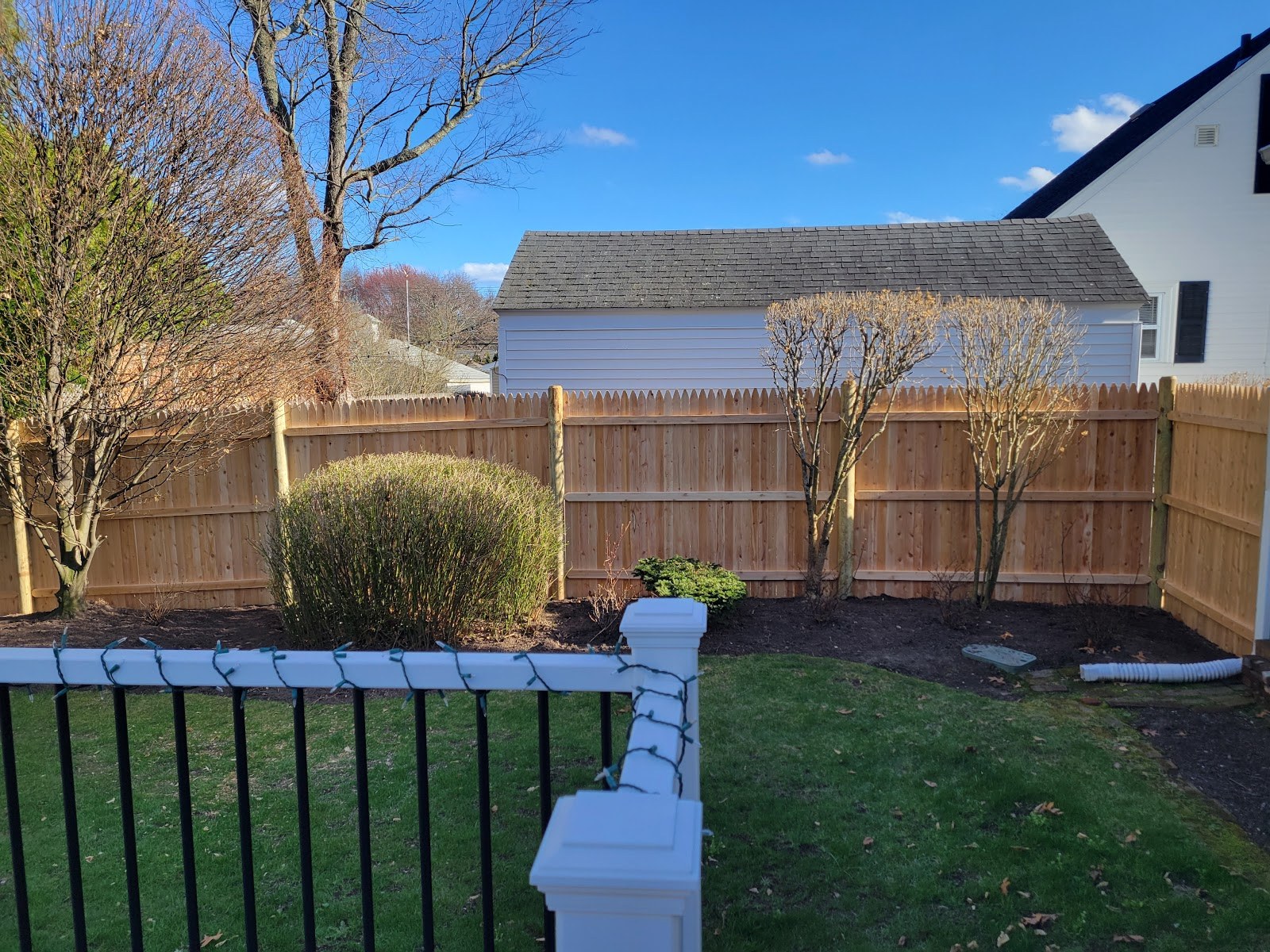 Cedar stockade fence and black ornamental fence installed in the same back yard by Professional World Fence