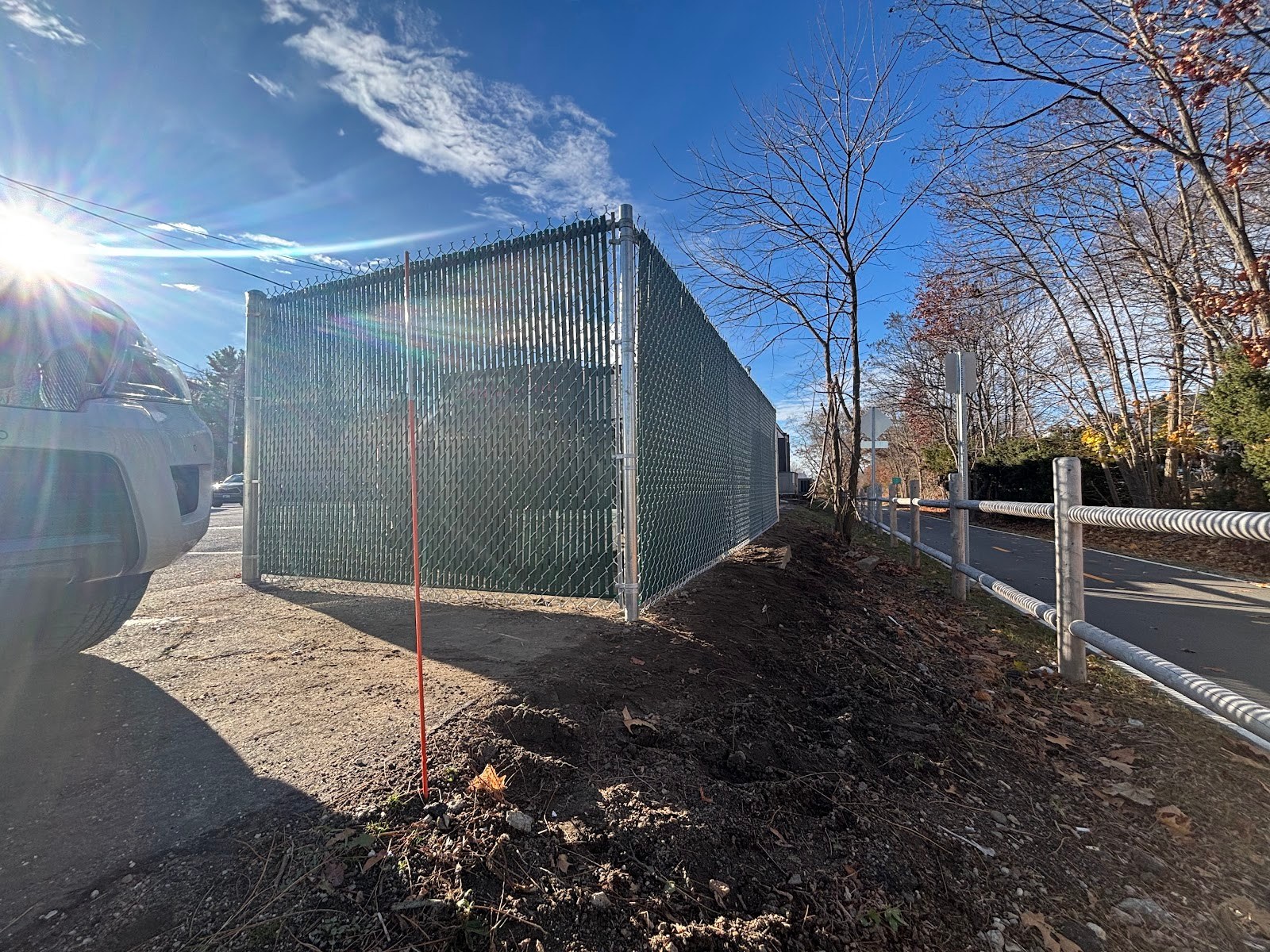 Green slatted chain link fence securing a commercial lot, installed by Professional World Fence