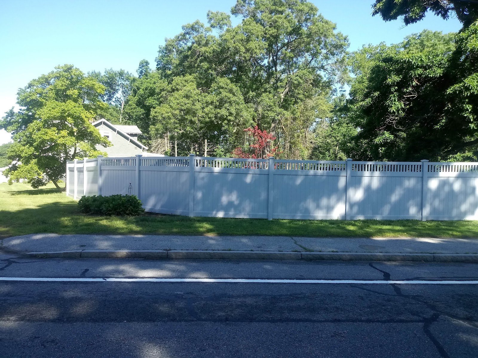 White PVC privacy fence with a spindle top run along a road by Professional World Fence
