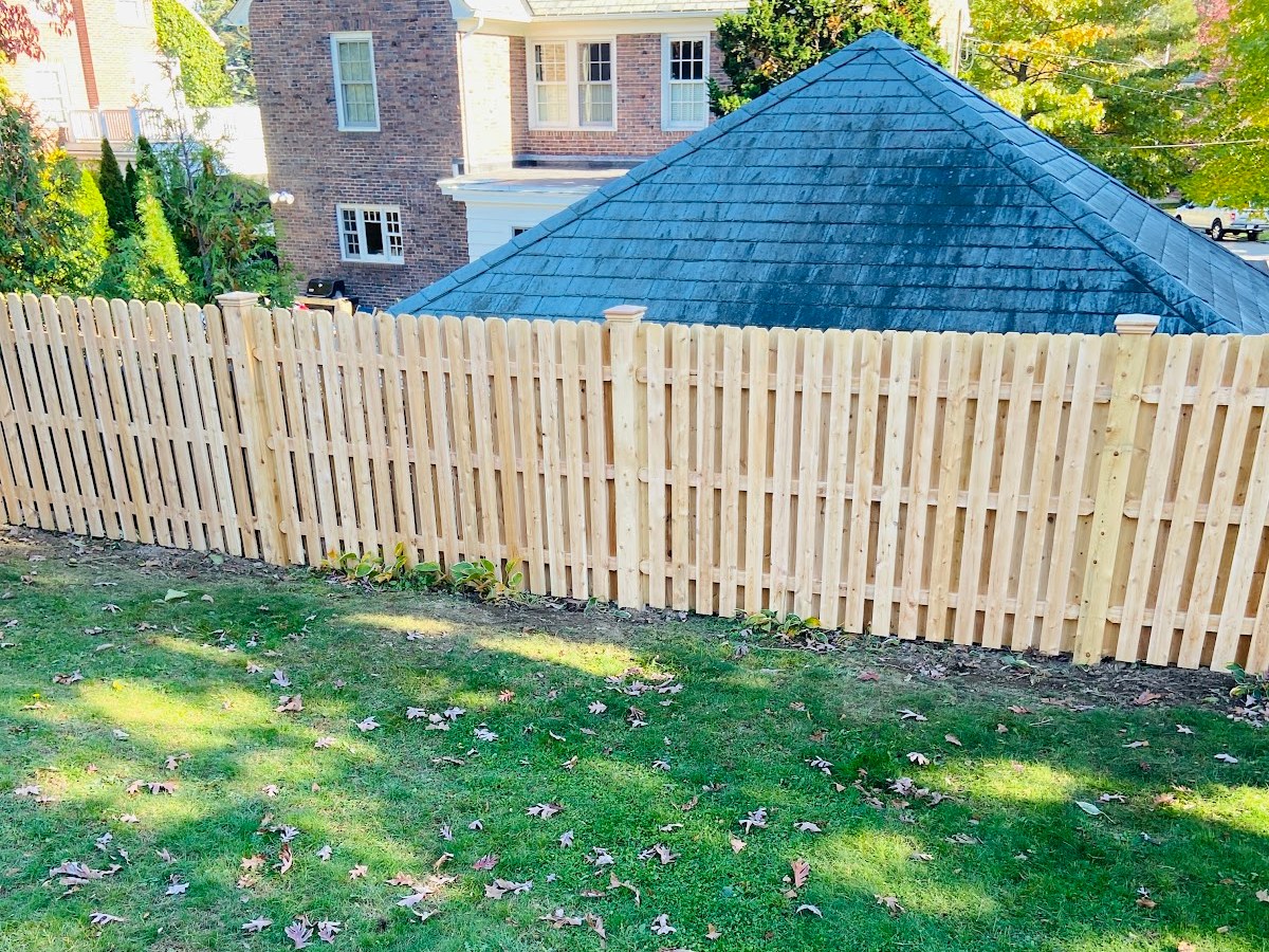 New cedar spaced picket fence enclosing a back lawn, installed by Professional World Fence
